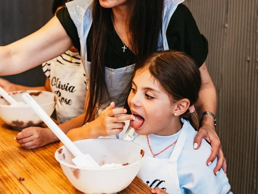 A girl tasting batter from a spatula at a macaron class at the Maison Fleuret school